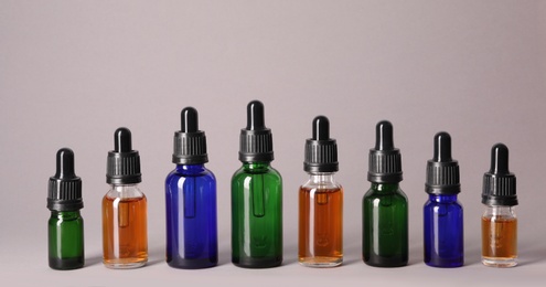 Cosmetic bottles of essential oils on color background