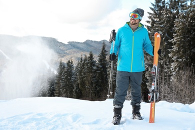 Man with ski equipment spending winter vacation in mountains