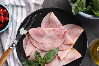 Photo of Tasty ham with basil, pickled peppers and carving fork on grey table, flat lay