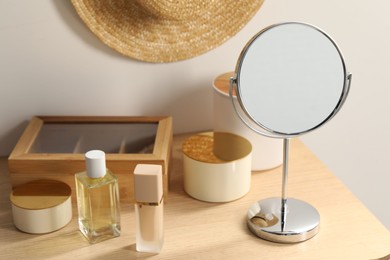 Photo of Mirror, perfume and makeup products on dressing table in room
