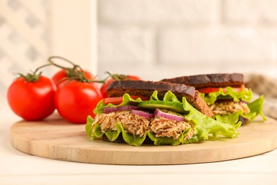 Delicious sandwiches with tuna and vegetables on white table