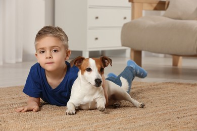 Little boy with his cute dog on floor at home, space for text. Adorable pet