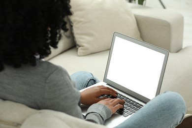 Woman using laptop on sofa indoors, closeup