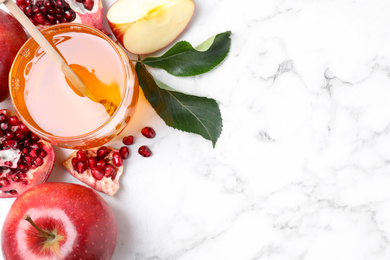 Photo of Honey, apples and pomegranate on white marble table, flat lay with space for text. Rosh Hashanah holiday
