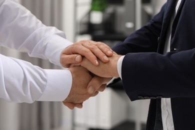 Photo of Trust and deal. Men joining hands in office, closeup