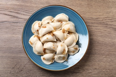 Photo of Plate of tasty cooked dumplings on wooden table, top view