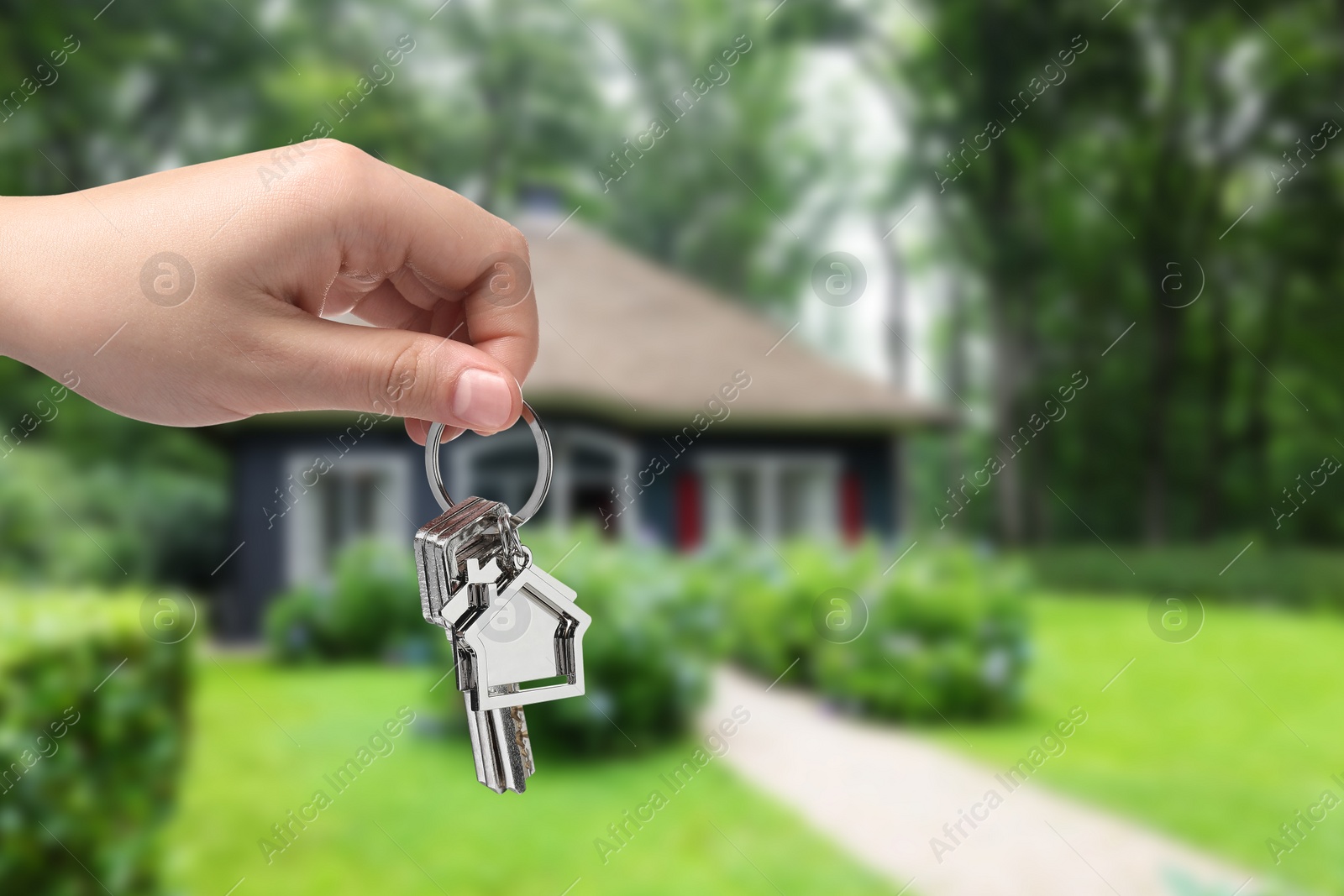 Image of Woman holding keys near house outdoors, closeup