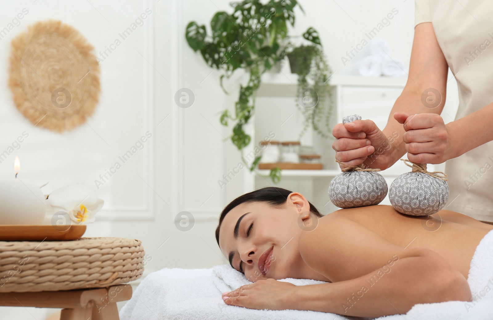 Photo of Young woman receiving herbal bag massage in spa salon