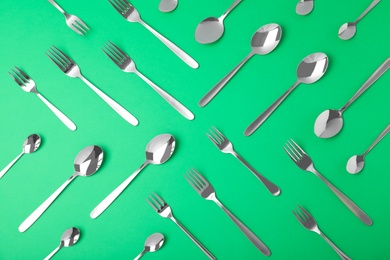 Set of new luxury cutlery on green background, flat lay