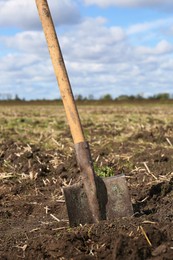 Shovel with wooden handle in field soil