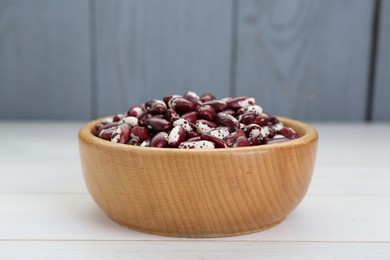 Photo of Bowl with dry kidney beans on white table, closeup