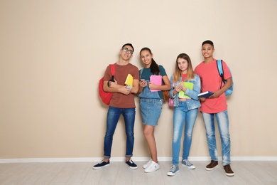 Photo of Group of teenagers against color wall, space for text. Youth lifestyle and friendship