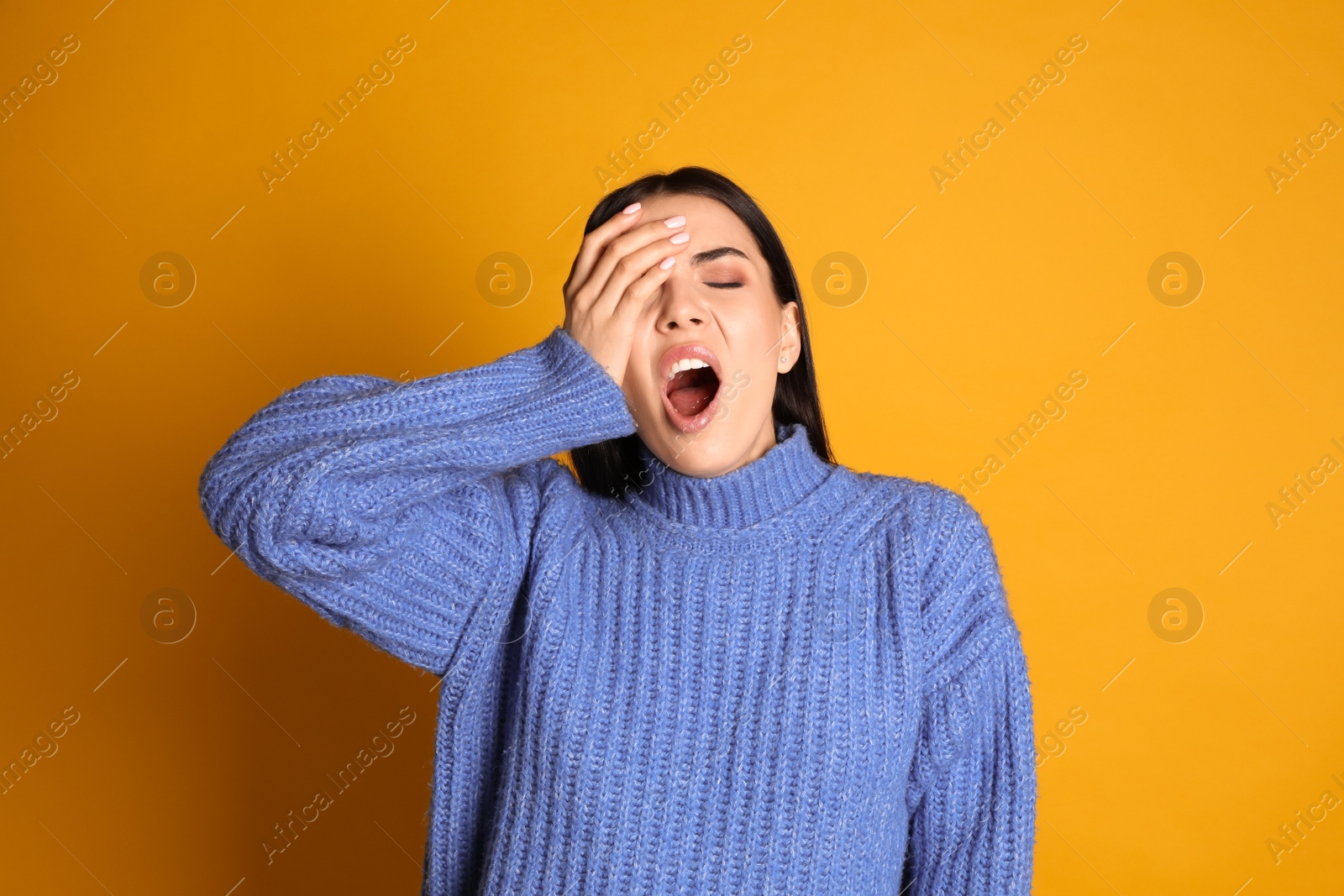 Photo of Young tired woman yawning on yellow background