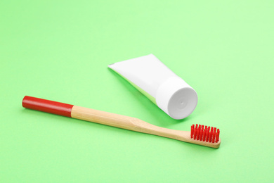 Natural bamboo toothbrush and paste on green background