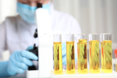 Photo of Test tubes with urine samples for analysis and blurred doctor on background, closeup