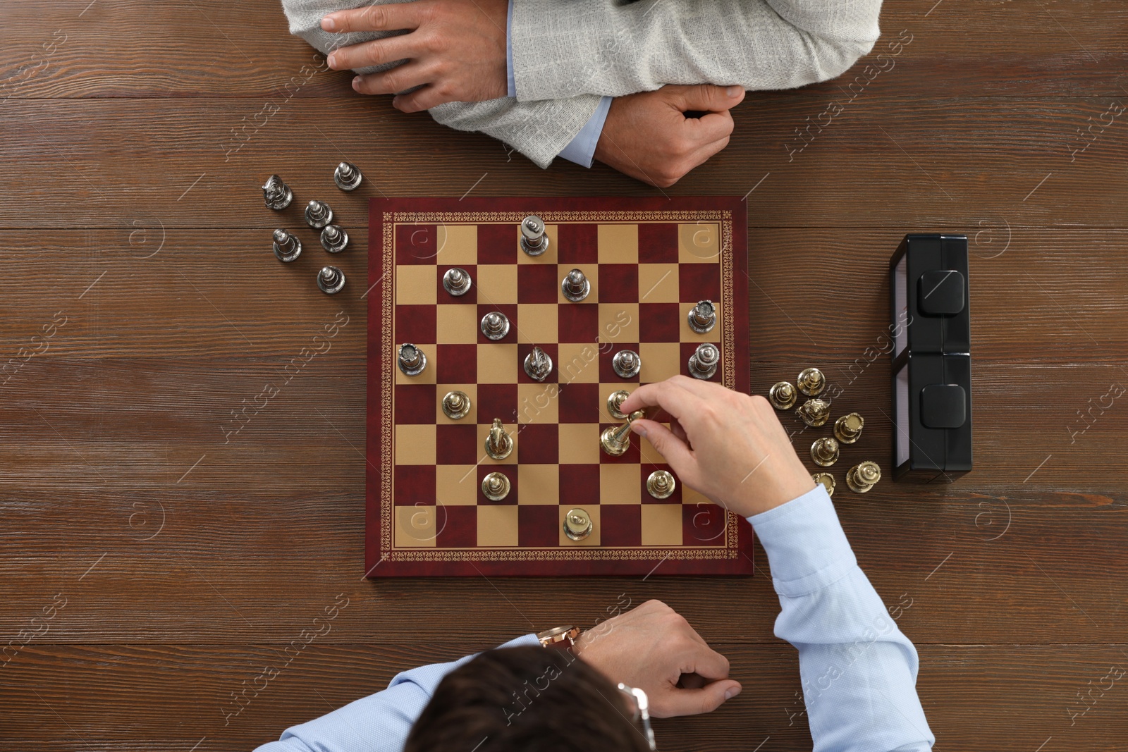 Photo of Men playing chess during tournament at wooden table, top view