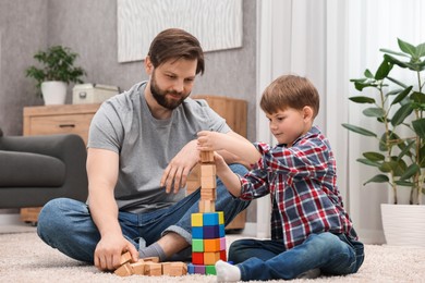 Photo of Dad and son building tower with cubes at home