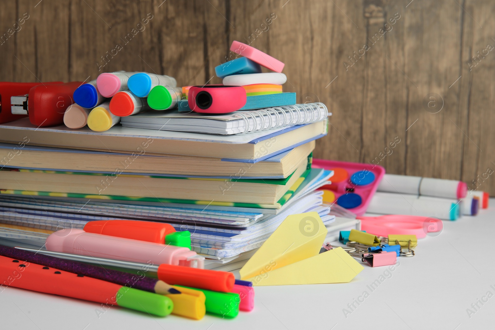 Photo of Many different books, paper plane and school stationery on white table, closeup. Back to school