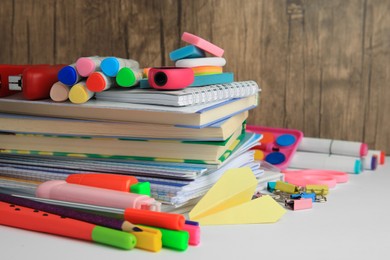 Photo of Many different books, paper plane and school stationery on white table, closeup. Back to school