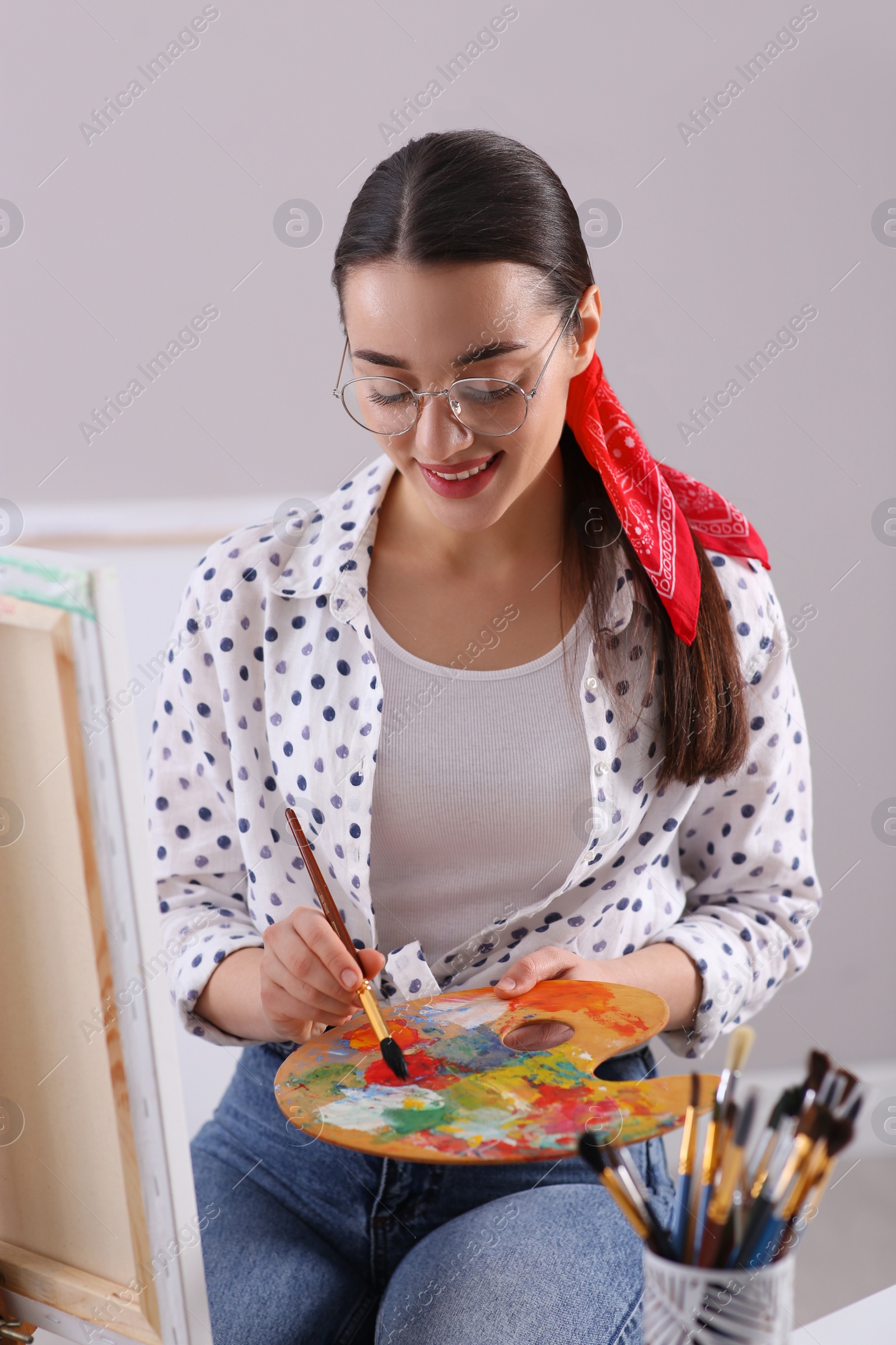 Photo of Happy woman artist drawing picture on canvas indoors