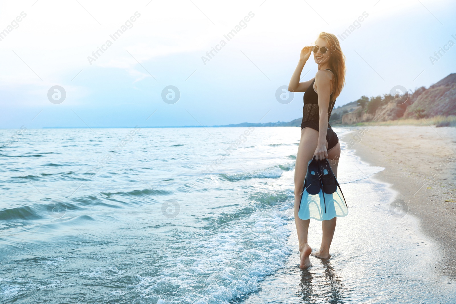 Photo of Happy woman with flippers near sea on beach