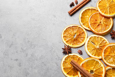 Dry orange slices, cinnamon sticks and anise stars on grey table, flat lay. Space for text