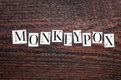 Photo of Word Monkeypox made of paper letters on wooden table, top view