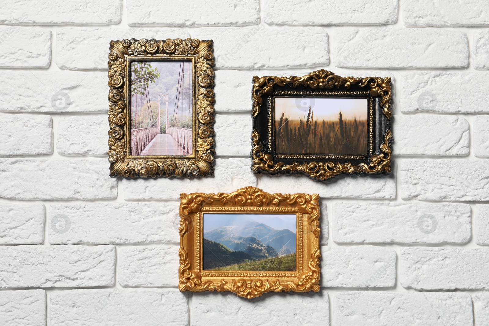 Photo of Vintage frames with photos of beautiful landscapes hanging on white brick wall