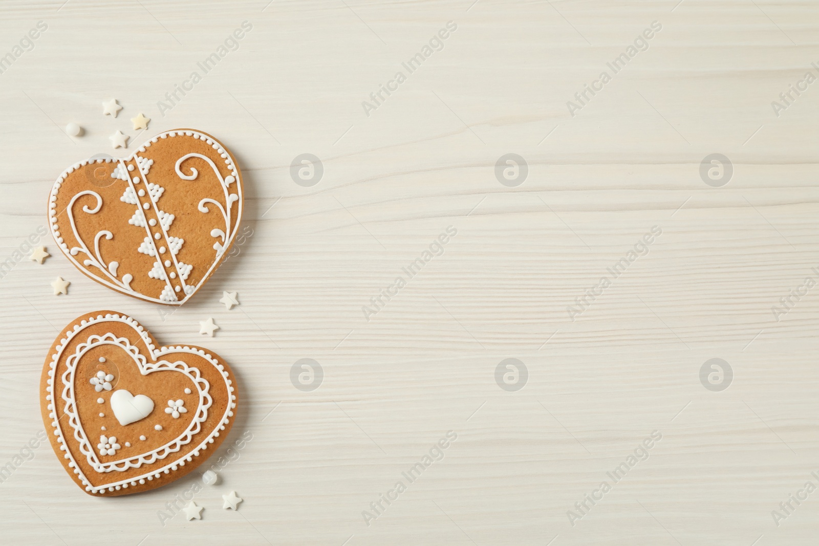 Photo of Tasty heart shaped gingerbread cookies on white wooden table, flat lay. Space for text