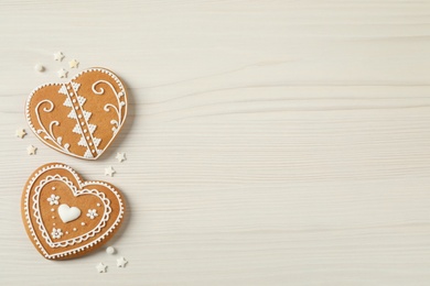 Photo of Tasty heart shaped gingerbread cookies on white wooden table, flat lay. Space for text