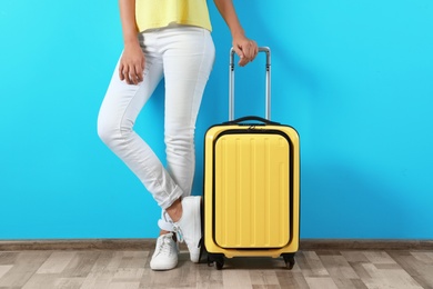 Photo of Woman with suitcase near color wall. Vacation travel