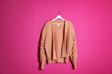 Hanger with stylish sweater on color background