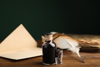 Feather pen, bottle of ink and old paper on wooden table