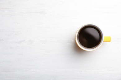 Photo of Ceramic cup with hot aromatic coffee on wooden background, top view