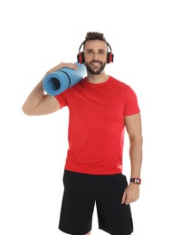 Handsome man with yoga mat and headphones on white background