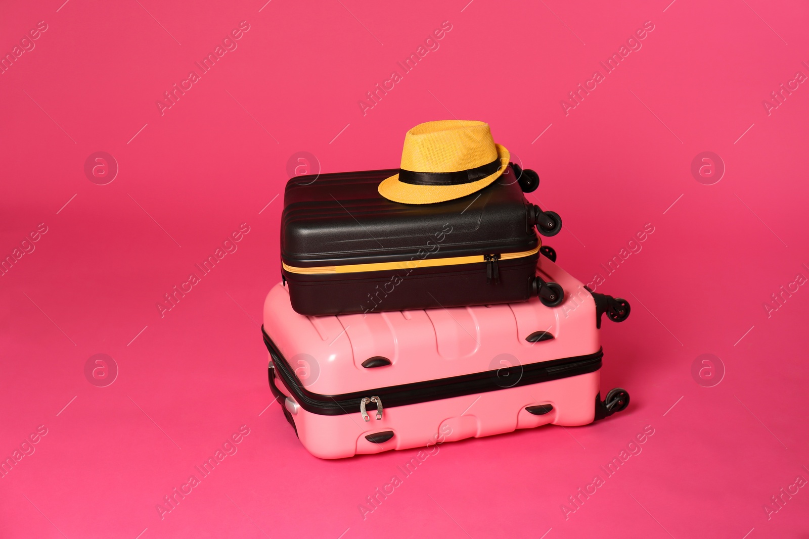 Photo of Stylish suitcases with hat on color background