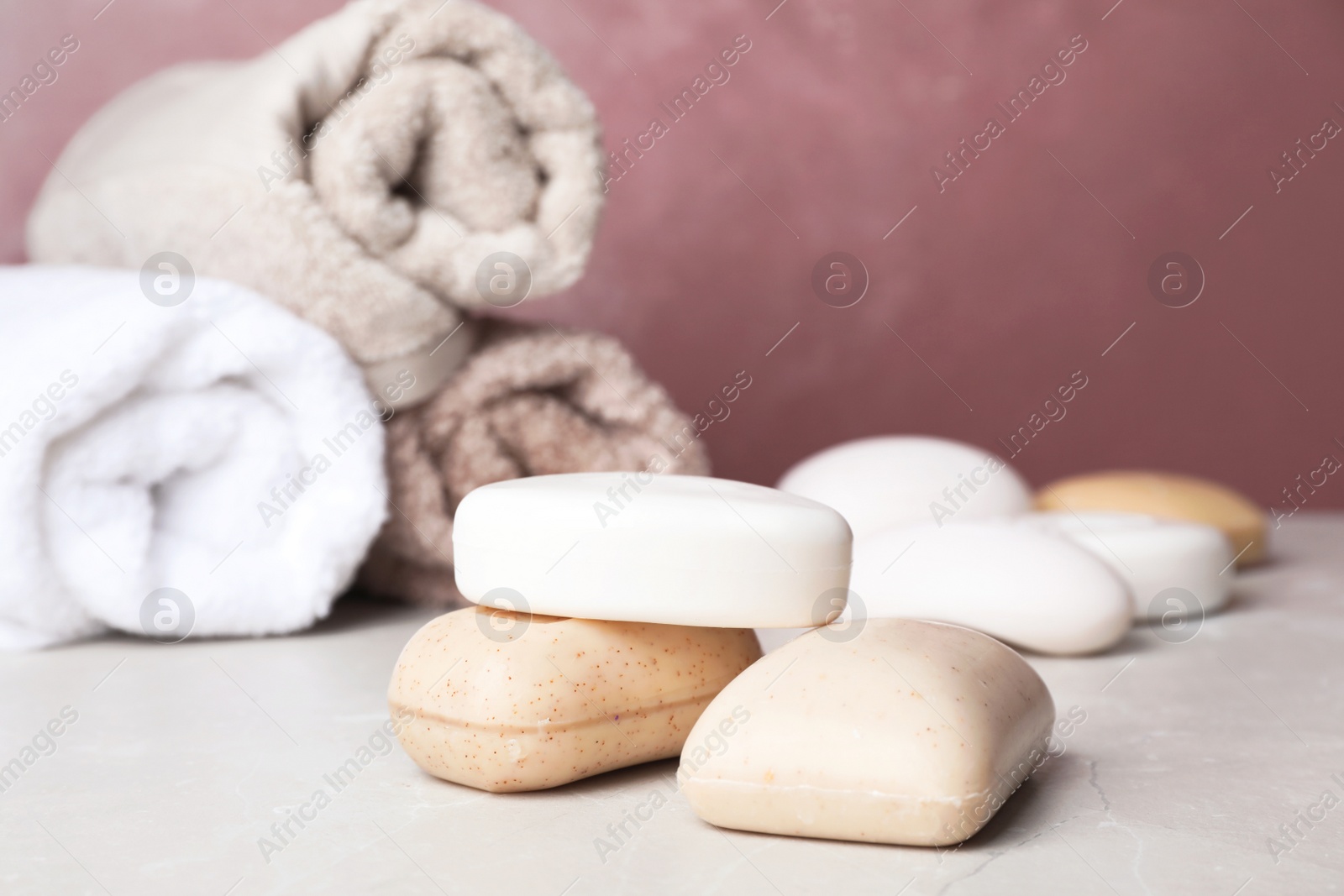 Photo of Different soap bars on light table against color background