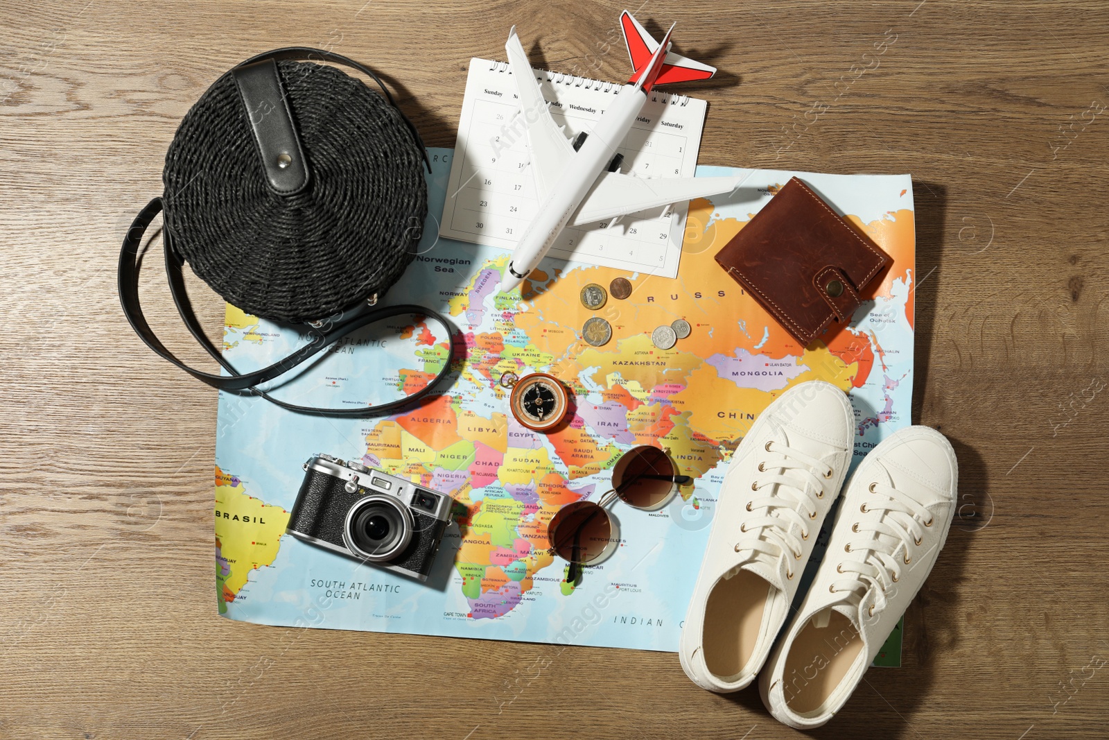 Photo of World map and items on wooden background, flat lay. Travel during summer vacation