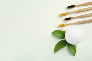 Photo of Bamboo toothbrushes and bowl of baking soda on beige background, flat lay. Space for text