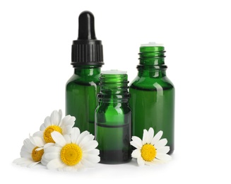 Photo of Chamomile flowers and cosmetic bottles of essential oil on white background