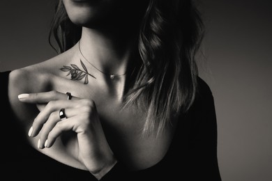Image of Young woman with tattoo on dark background, closeup. Black and white photography
