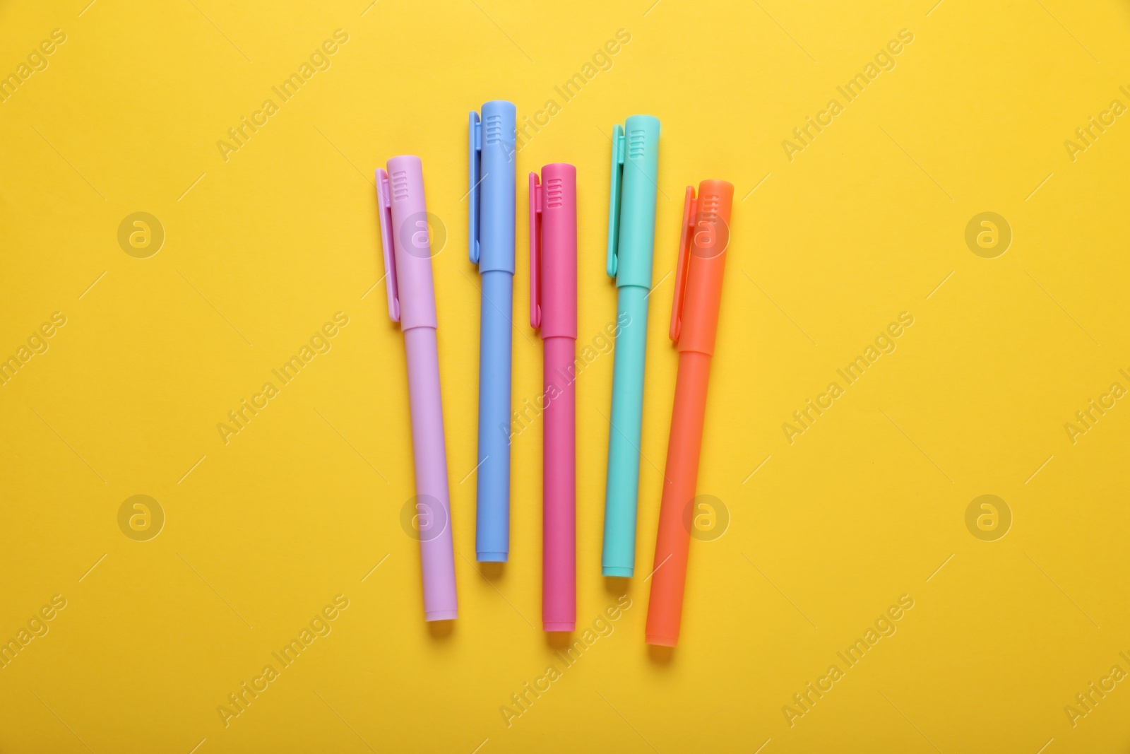 Photo of Many colorful markers on yellow background, flat lay