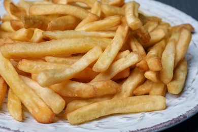 Plate of tasty french fries on table, closeup