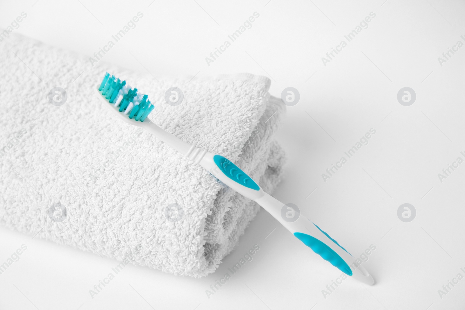 Photo of Light blue toothbrush and terry towel on white background