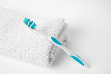 Photo of Light blue toothbrush and terry towel on white background