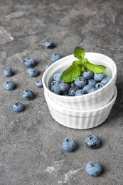 Crockery with juicy and fresh blueberries on color table