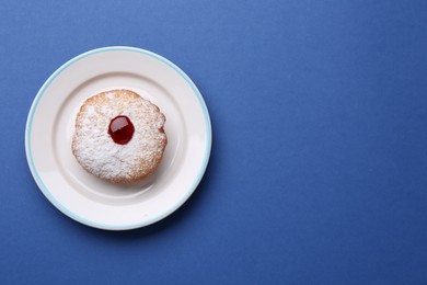 Hanukkah donut with jelly and powdered sugar on blue background, top view. Space for text