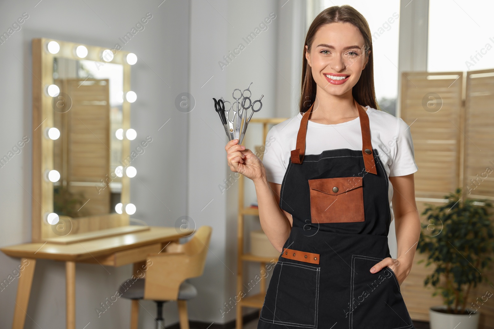 Photo of Portrait of happy hairdresser with professional scissors in beauty salon