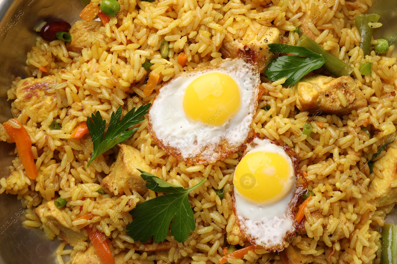 Photo of Tasty rice with meat, eggs and vegetables in frying pan, top view