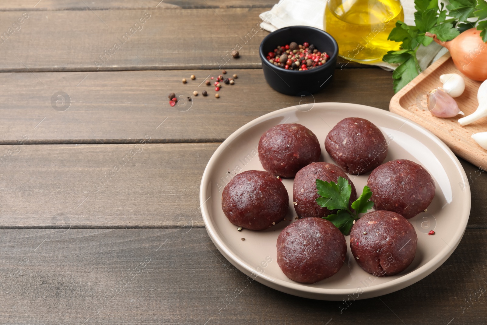 Photo of Many fresh raw meatballs on wooden table, space for text